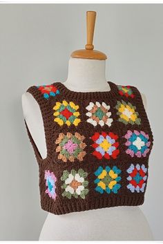 a white mannequin wearing a brown crochet top with multicolored flowers