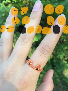 a woman's hand with an orange and black dotted ring on top of it