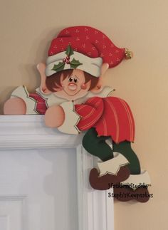 a christmas decoration hanging on the wall next to a white door with a red and green elf hat