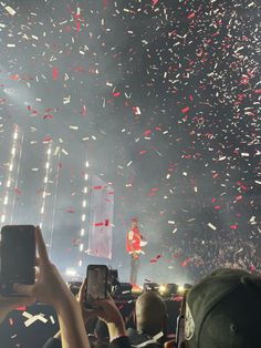 confetti is thrown in the air at a concert as people take pictures on their cell phones