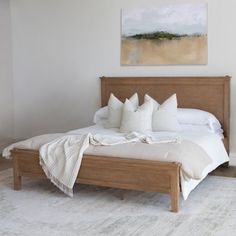 a bed with white linens and pillows in a small room next to a painting on the wall