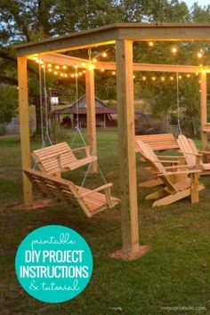 a wooden swing set in the middle of a grassy area with string lights strung over it