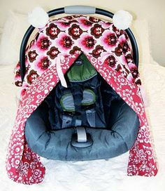 a baby car seat covered in pink and red fabric with flowers on the front cover