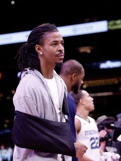 a man with dreadlocks standing in front of other people at a basketball game