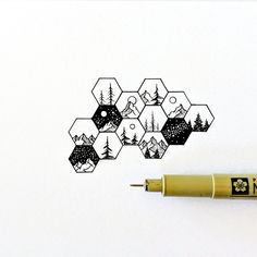 a pen is sitting next to a drawing of trees and mountains in hexagons