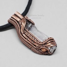 a wire wrapped pendant is shown on a black leather necklace with crystal stones in the center