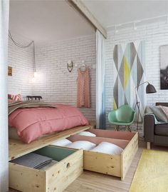 a bedroom with white brick walls and pink bedding, drawers under the bed are open