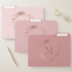 three pink file folders with gold foil leaves and the letter m on each side