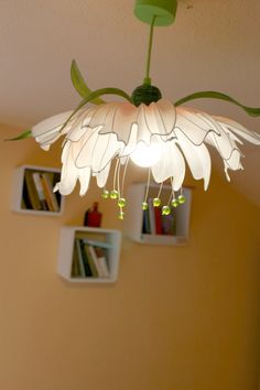a white flower hanging from the ceiling in a room with bookshelves behind it