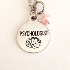 a white key chain with a silver disc and a pink bead hanging from it