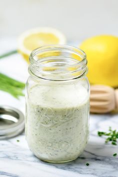 a jar filled with dressing sitting on top of a counter next to a lemon and knife