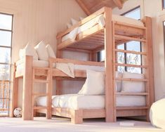 bunk beds in a bedroom with white pillows and wood walls, along with large windows