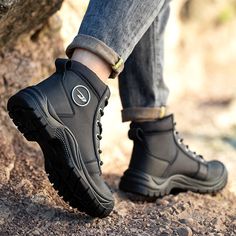 a person wearing black boots standing on top of a rock