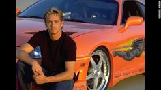a man sitting on the ground next to an orange sports car with words paul walker