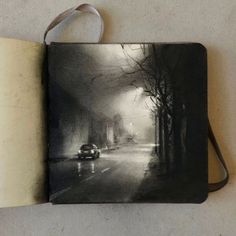 an open book with a black and white image of a car driving down the road
