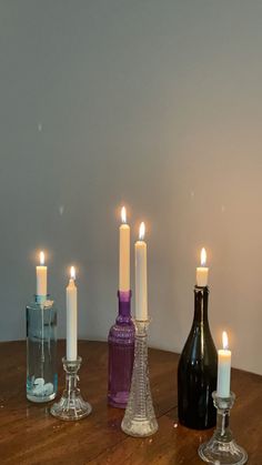 there are many candles that are on the table with wine bottles in front of them