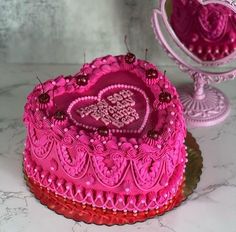 a pink heart shaped cake sitting on top of a table next to a small mirror