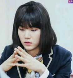 a young woman sitting at a table with her hands together