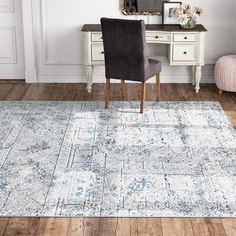 a white and blue area rug with an ornate design on the floor in front of a chair