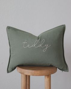 a green pillow sitting on top of a wooden stool