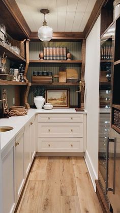 a kitchen filled with lots of wooden shelves and white counter top next to a sink