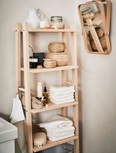 a wooden shelf with towels and other items on it next to a mirror in a bathroom