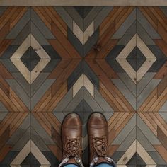 a pair of brown shoes sitting on top of a wooden floor next to a wall