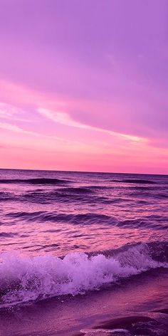 an ocean with waves coming in to the shore and purple sky at sunset or dawn