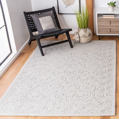 a living room with white walls and wood flooring is pictured in this image, the rug has an intricate design on it