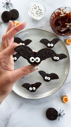 a plate with cookies decorated to look like bats and googly eyes on it, surrounded by halloween decorations