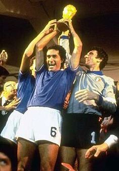 two soccer players holding up the trophy in front of their head while others look on