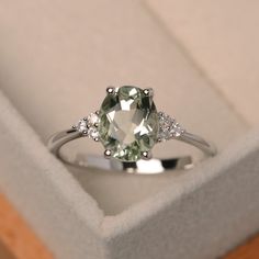 This ring features a 7*9mm oval cut natural green amethyst and sterling silver finished with rhodium. Customization is available. It is made by hand, and it will take about 7 days to finish the ring after your payment is completed. Main stone: Natural green amethyst Main stone weight: Approx 1.55 ct Metal type: sterling silver finished with rhodium/14k gold I can make it with 14k solid gold(rose/yellow/white) and diamond accent stone option, just feel free to contact me. Any question, just let m Light Green Engagement Ring, Green Wedding Rings, Green Engagement Rings, Ring Green Stone, Green Stone Ring, Amethyst Wedding, Green Gemstone Ring, Silver Rings With Stones, Green Amethyst Ring