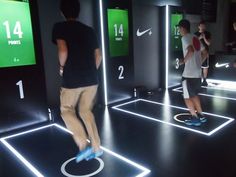 two men are playing video games in a room with neon lights on the walls and floor