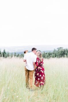 a man and woman are standing in the tall grass with their arms around each other