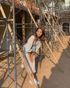 a woman leaning on the scaffolding in front of a building