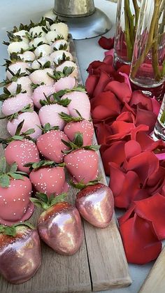there are many strawberries on the wooden board next to each other and flowers in vases