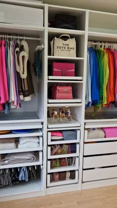 an organized closet with white drawers and lots of colorful clothing hanging on the shelves,