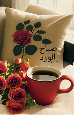 a cup of coffee and some roses on a couch with a pillow in the background