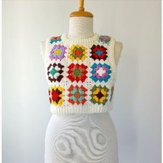 a white mannequin wearing a multicolored knitted top with flowers on it