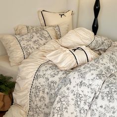 an unmade bed with white and black comforter, pillows and pillowcases