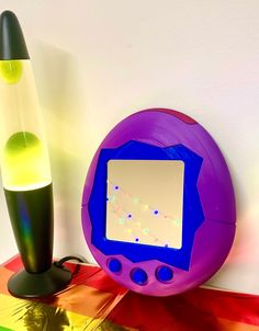 an electronic device sitting on top of a table next to a colorful vase and lamp