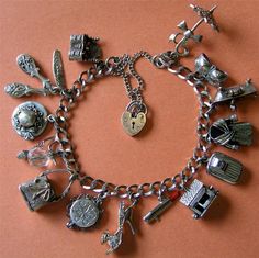 a charm bracelet with various charms on an orange background, including keys and other items