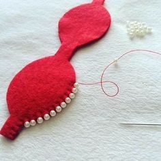 a red piece of fabric with pearls on it next to a pair of scissors and thread