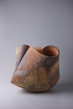 a brown vase sitting on top of a white table next to a gray wall and floor