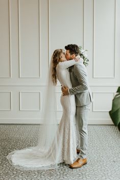 a bride and groom kissing in front of a wall with white paneled walls behind them
