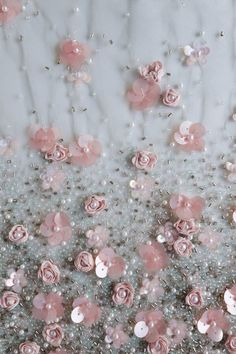 some pink flowers and pearls on a white table cloth with silver beads in the middle