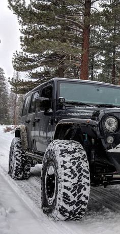 a black jeep driving down a snow covered road