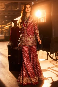 Embark on a journey of cultural elegance with our enchanting Pant Suit, a masterpiece inspired by the rich tapestry of Persian culture. Adorned with mesmerizing geometric patterns, delicate domes, and intricate Tree Motifs, this suit weaves a tale of a woman's journey, capturing the emotions of a bride on her special day. Drenched in a passionate red hue, the ensemble features a beautifully embroidered jacket paired with flared pants and a chic bustier. Redefine bridal couture with this fusion of tradition and modernity, designed for brides who exude both timeless charm and contemporary flair. Elevate your wedding day style with this symbolic and stunning creation, celebrating the essence of love and cultural heritage. FABRIC DETAILS: JACKET - RAW SILK, PANTS - RAW SILK, BUSTIER - RAW SILK Pant Suit Designs Indian Style, Flared Pants Outfit Indian, Bridal Suits For Women Indian, Lehenga With Jacket, Red Pantsuit, Suits For Women Indian, Western Gowns, Couture 2024, Traditional Blouse