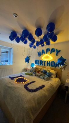 a bedroom decorated in blue and white with balloons on the ceiling, birthday cake and decorations