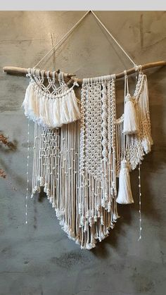 a wall hanging made out of macrame and tassels on a wooden stick